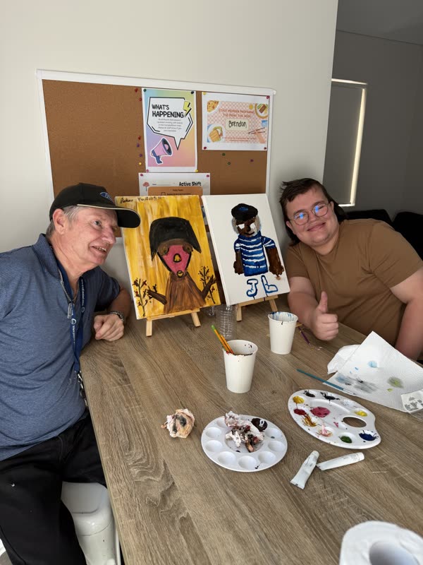 Two Dream Maker participants smiling beside their finished paintings